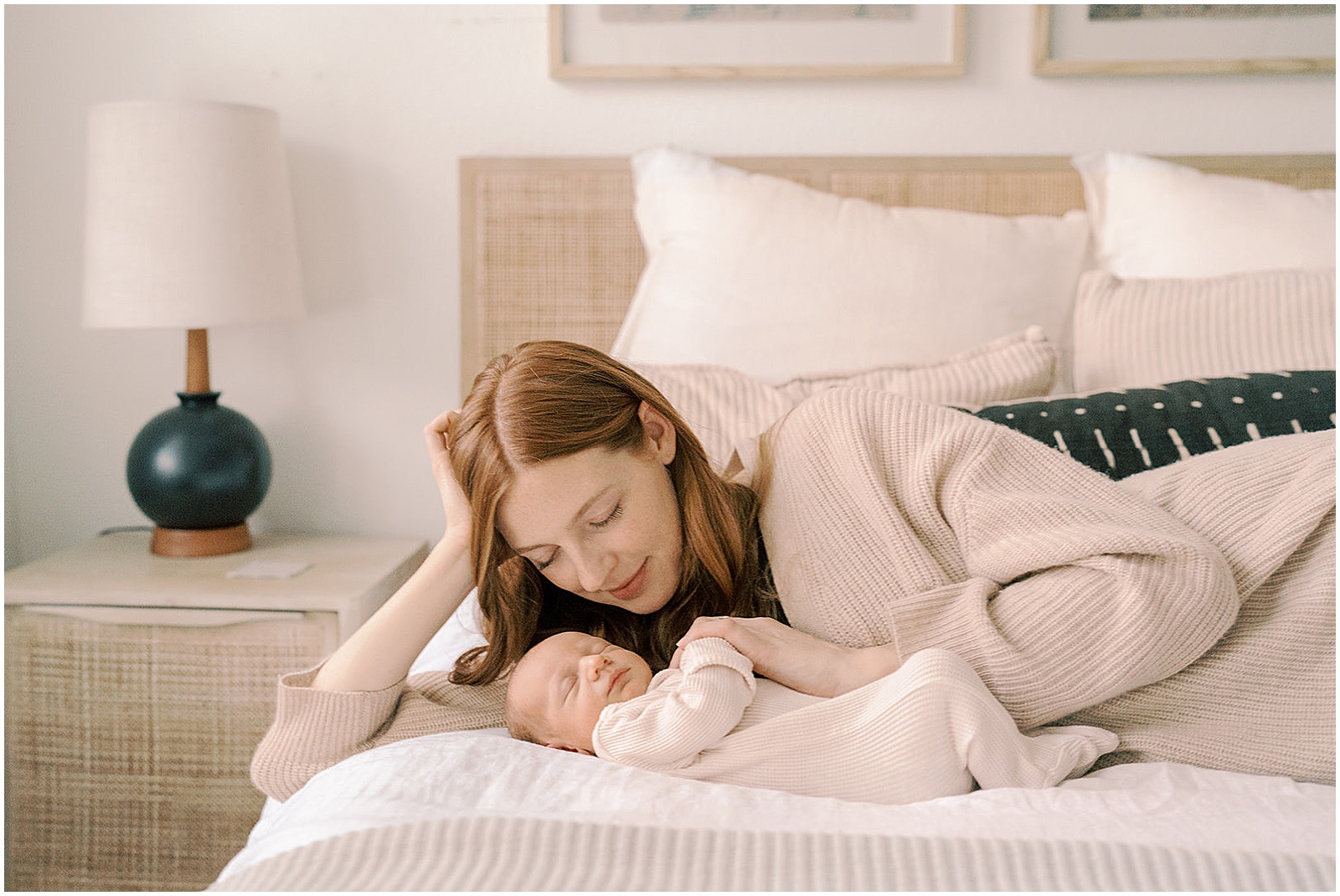 A mother lays on a bed with a baby for newborn photography.