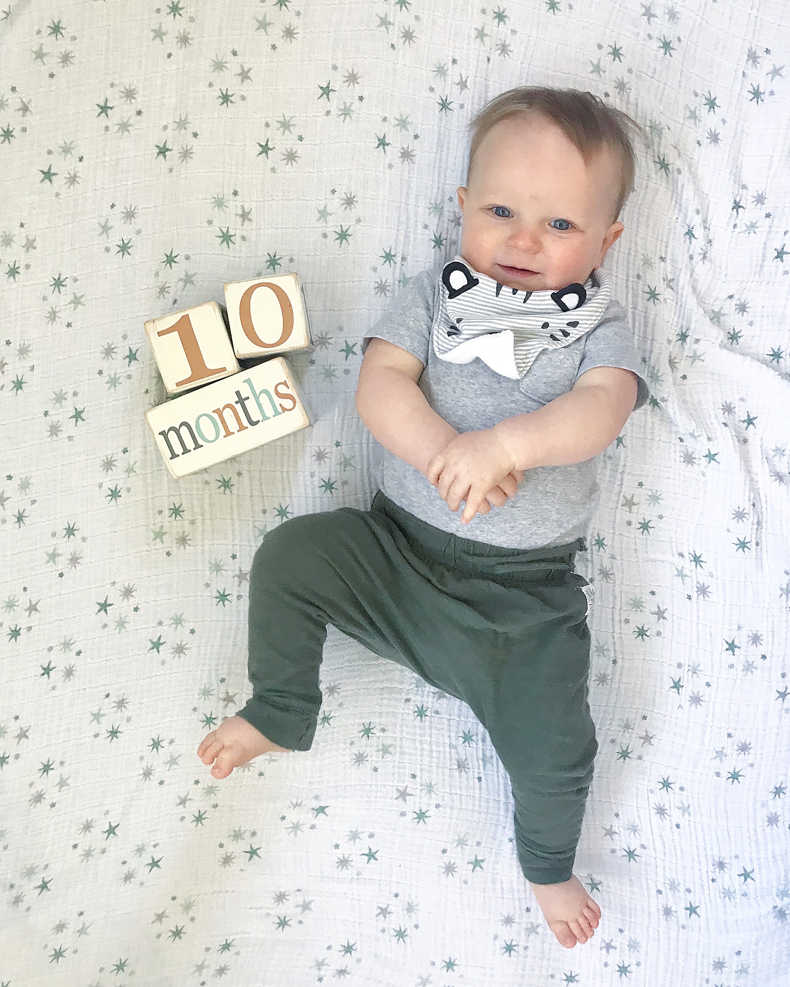 A baby lays beside blocks for a ten month photo.