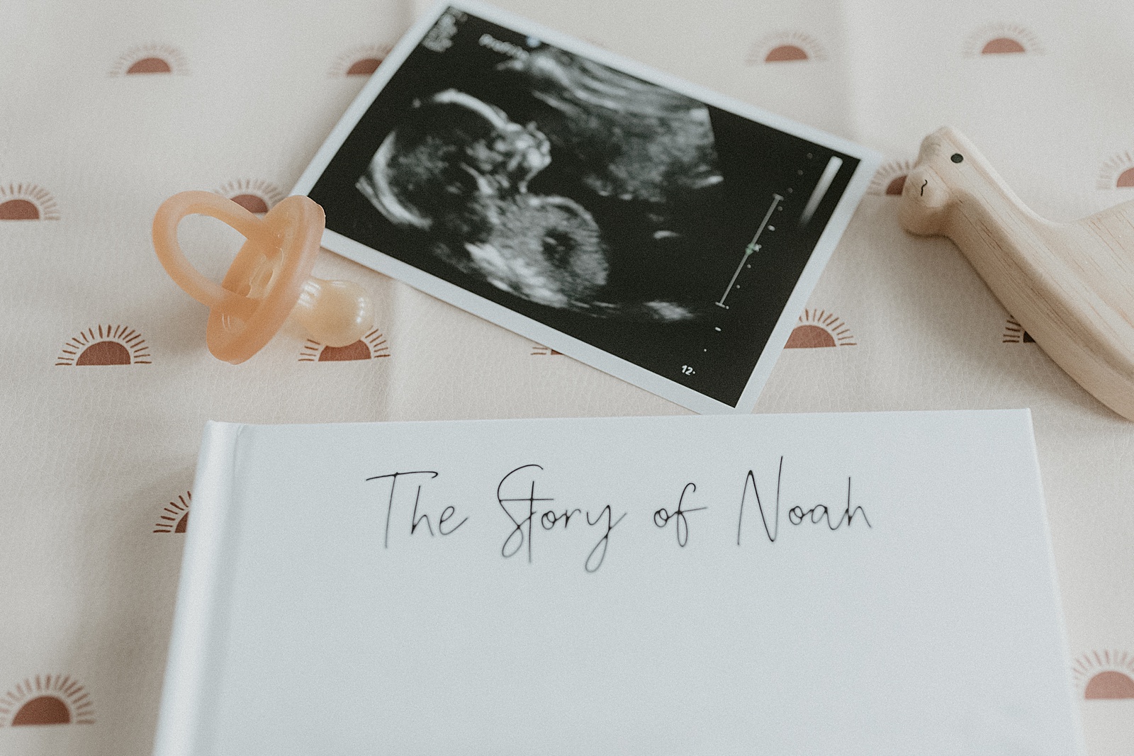 An ultrasound and pacifier sit beside a custom baby book.