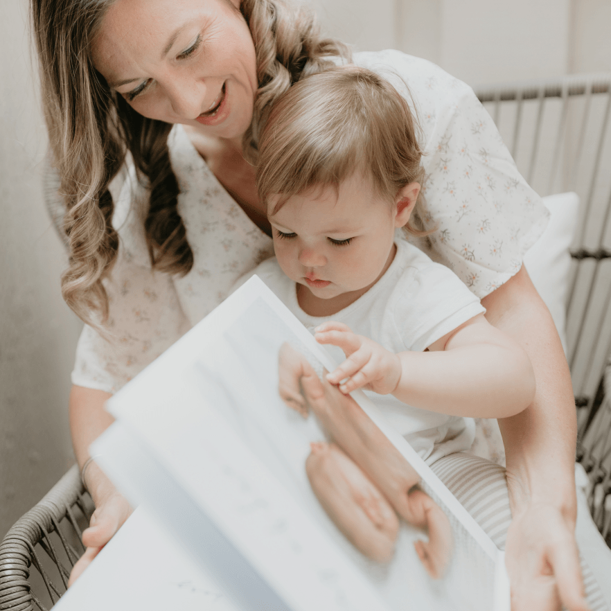 Mom with her toddler on her lap looking at a modern baby book